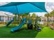 Community playground with slides and climbing features on green turf, shaded by a large blue canopy for enjoyable play at 16516 Bridgewalk Dr, Lithia, FL 33547