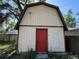 Outdoor view showing a detached garage with tan siding and a red door at 1703 N Taylor Rd, Brandon, FL 33510