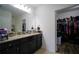 Bathroom vanity with granite countertop, dark cabinets, and a view of a walk-in closet at 19047 Alfaro Loop, Spring Hill, FL 34610