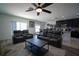 Inviting living room featuring dark furniture, ceiling fan, and seamless transition into kitchen at 19047 Alfaro Loop, Spring Hill, FL 34610