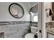 A stylish powder room featuring neutral paint, attractive wall tiles, and a round mirror over the toilet at 1910 Elk Spring Dr, Brandon, FL 33511