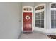 Close-up of welcoming red front door, decorative wreath, and sidelight windows at 2010 Rutherford Dr, Dover, FL 33527