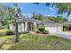 Charming single-story home featuring lush landscaping, a red door, and a three-car garage at 2010 Rutherford Dr, Dover, FL 33527