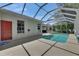 View of the screen-enclosed pool with concrete deck and exterior red door at 2010 Rutherford Dr, Dover, FL 33527