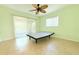 Bedroom features light green walls, a ceiling fan, tile flooring, and sliding glass doors to the patio at 2211 Harrison Dr, Holiday, FL 34691