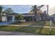 Charming single-story home with a well-maintained front yard, mature palm trees, and an attached two-car garage at 2211 Harrison Dr, Holiday, FL 34691