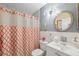 This bathroom features a vanity with white cabinets, a round mirror, and a decorative shower curtain at 2221 Swedish Dr # 55, Clearwater, FL 33763