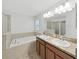 Bathroom featuring a bathtub, a glass shower, and dual sinks set in granite counters at 2405 Dakota Rock Dr, Ruskin, FL 33570