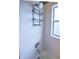 Close up of shower head with shelving in a shower-tub combo with tile surround at 2604 Clareside Dr, Valrico, FL 33596