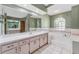 A spacious bathroom featuring dual sinks, a soaking tub, natural light, and neutral tones at 3001 Folklore Dr, Valrico, FL 33596