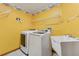 Laundry room features washer, dryer, wash sink, shelves and bright yellow walls at 3001 Folklore Dr, Valrico, FL 33596