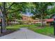 Beautifully landscaped exterior of a beige building with red accents and mature trees at 3062 Eastland Blvd # 402, Clearwater, FL 33761