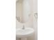 Powder room featuring a pedestal sink, oval mirror, and neutral tones, creating a clean and modern aesthetic at 32803 Pez Landing Ln, Wesley Chapel, FL 33543