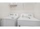 Modern laundry room featuring white washer and dryer units with convenient overhead shelving at 32803 Pez Landing Ln, Wesley Chapel, FL 33543