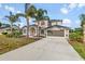 Two-story home featuring palm trees, arched windows, a covered entryway, and an attached two-car garage at 3434 St Ives Blvd, Spring Hill, FL 34609