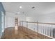 Upstairs hallway boasts wood flooring, a white railing, and natural light at 3434 St Ives Blvd, Spring Hill, FL 34609