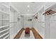 Spacious walk-in closet with custom shelving, wooden floor, and a central pink ottoman on a white shag rug at 3501 W Tacon St, Tampa, FL 33629