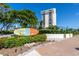 Siesta Key Village sign with tropical landscaping and high-rise building in the background at 396 Avenida Madera, Sarasota, FL 34242