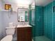 A modern bathroom featuring a wood vanity, floating shelf, and an updated shower with glass door and green tile at 4610 Cypress S Way, St Petersburg, FL 33705