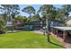 Well-manicured lawn leads to a modern home with a vibrant turquoise door and mature trees in the background at 4610 Cypress S Way, St Petersburg, FL 33705