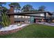 Striking home featuring a modern design with a turquoise door, brick accents, and a lush green lawn at 4610 Cypress S Way, St Petersburg, FL 33705