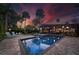 Twilight view of the backyard pool, highlighted by landscape lighting and colorful sunset at 4610 Cypress S Way, St Petersburg, FL 33705
