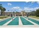 Community shuffleboard courts with lush green surroundings, palm trees, and residential buildings in the background at 467 Boca Ciega Point S Blvd, St Petersburg, FL 33708