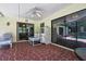 Enclosed patio with brick flooring, ceiling fan, seating, and views of the sparkling backyard pool at 5042 Gaston St, Spring Hill, FL 34607
