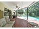 Enclosed patio with brick flooring, ceiling fan, grill, seating, and views of the sparkling backyard pool at 5042 Gaston St, Spring Hill, FL 34607