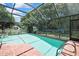 Beautiful backyard pool with screen enclosure, surrounded by a brick patio and landscaping at 5042 Gaston St, Spring Hill, FL 34607