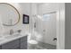Modern bathroom featuring a glass-enclosed shower, round mirror, and stylish vanity with gray cabinets at 5043 Night Star Trl, Odessa, FL 33556