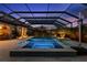Stunning nighttime view of the screened-in pool and spa with lush landscaping at 5043 Night Star Trl, Odessa, FL 33556