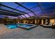 A screened in pool and integrated spa are illuminated at dusk, with lounge chairs nearby at 5043 Night Star Trl, Odessa, FL 33556