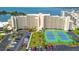An aerial view of a condo complex, tennis courts, the bay, and neatly landscaped grounds at 6009 Sea Ranch Dr # 107E, Hudson, FL 34667