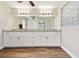 Bright bathroom featuring wood floors, double vanity, granite countertops and large mirror at 6080 Taneytown St, North Port, FL 34291