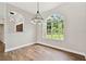 Bright dining area featuring wood floors, neutral walls, large window with backyard view and modern lighting fixture at 6080 Taneytown St, North Port, FL 34291
