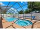 Beautiful screened-in pool and hot tub with blue water, surrounded by a brown patio and privacy fence at 6365 32Nd N Ave, St Petersburg, FL 33710