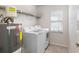 Functional laundry room featuring a washing machine, dryer, hot water tank, storage shelf and a window at 6604 Dolphin Cove Dr, Apollo Beach, FL 33572