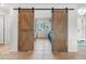 View of the living room from the bedroom through the open barn doors that lead to the spacious area beyond at 6604 Dolphin Cove Dr, Apollo Beach, FL 33572