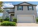Two-story gray home featuring a two-car garage, manicured landscaping, and complementary dark shutters at 6653 Mineral Springs Rd, New Port Richey, FL 34653