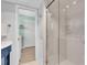 Bright bathroom featuring glass shower, blue vanity, and view into laundry room at 860 Harbor Is, Clearwater Beach, FL 33767