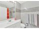 Stylish bathroom featuring gray tiles, a sink with a white vanity, and a shower with an orange curtain at 9013 Nakoma Way, Weeki Wachee, FL 34613