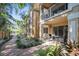 Exterior view of a condo building with patios, balconies, brick walkway, and tropical landscaping at 950 Broadway # 103, Dunedin, FL 34698