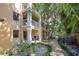 Multi-story condo building exterior featuring private balconies, lush greenery, and a paver walkway at 950 Broadway # 103, Dunedin, FL 34698