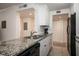 Modern kitchen featuring granite countertops, black appliances, and sleek white cabinetry at 950 Broadway # 103, Dunedin, FL 34698