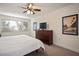 Bedroom featuring ceiling fan, large window, and dresser with TV at 950 Broadway # 103, Dunedin, FL 34698