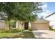 Charming single-Gathering home featuring a manicured lawn, mature tree, and a two-car garage at 10036 Crested Fringe Dr, Riverview, FL 33578