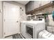 Functional laundry room with washer, dryer, storage cabinets, and charming decor at 10036 Crested Fringe Dr, Riverview, FL 33578