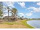 Scenic view of a tranquil pond near community residences, enhanced by lush greenery and palm trees at 10036 Crested Fringe Dr, Riverview, FL 33578