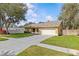 Inviting home with a green lawn, mature trees, and a driveway leading to an attached two-car garage at 1017 Hamilton Ave, Tarpon Springs, FL 34689